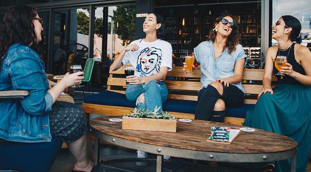 Four people sitting around a table, holding drinks.