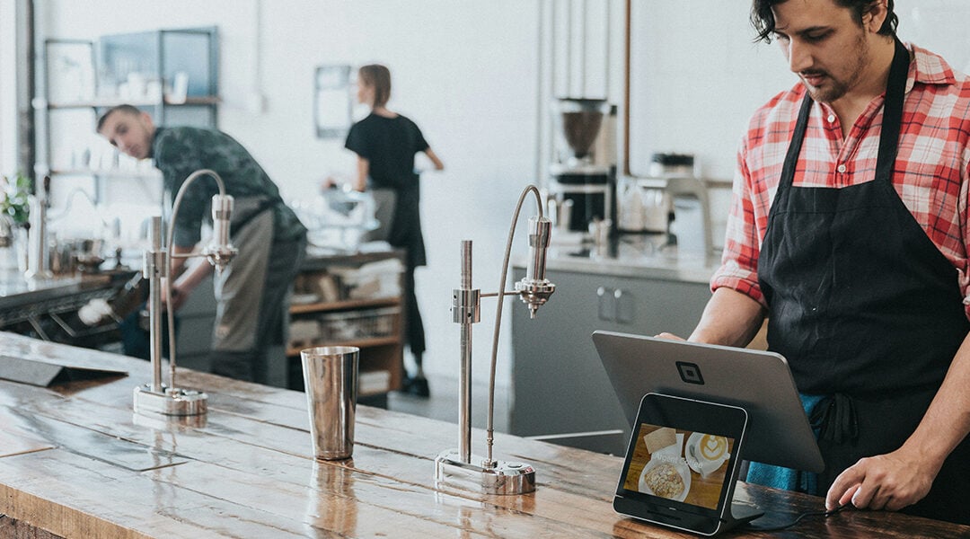 Cashier standing at a point of sale system in specialty coffee shop.