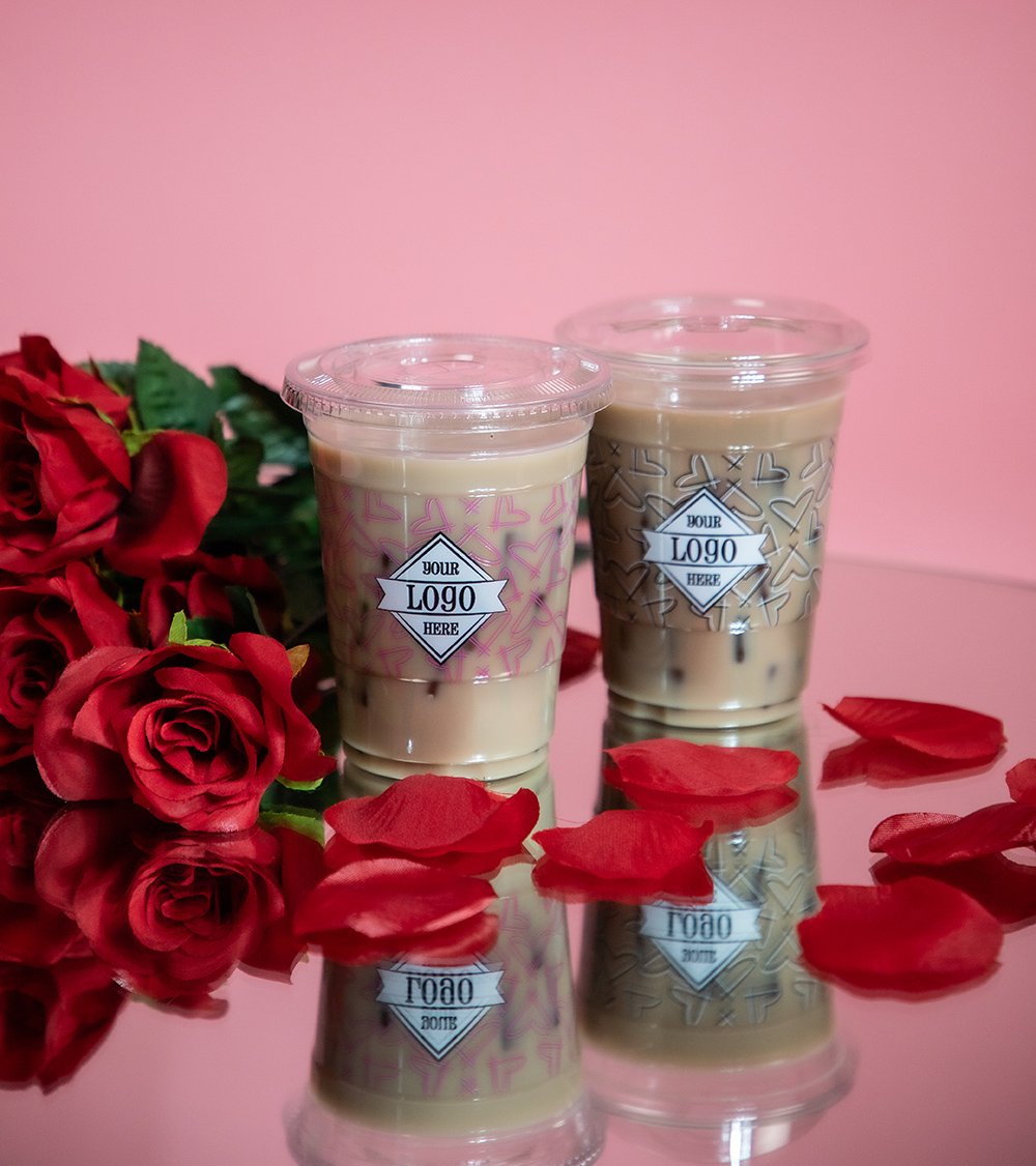 Valentine's Day themed cups on a mirror with rose petals and pink backdrop.