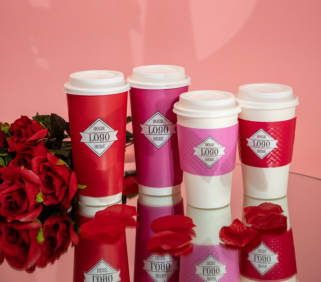 Valentine's Day themed cups on a mirror with rose petals and pink backdrop.