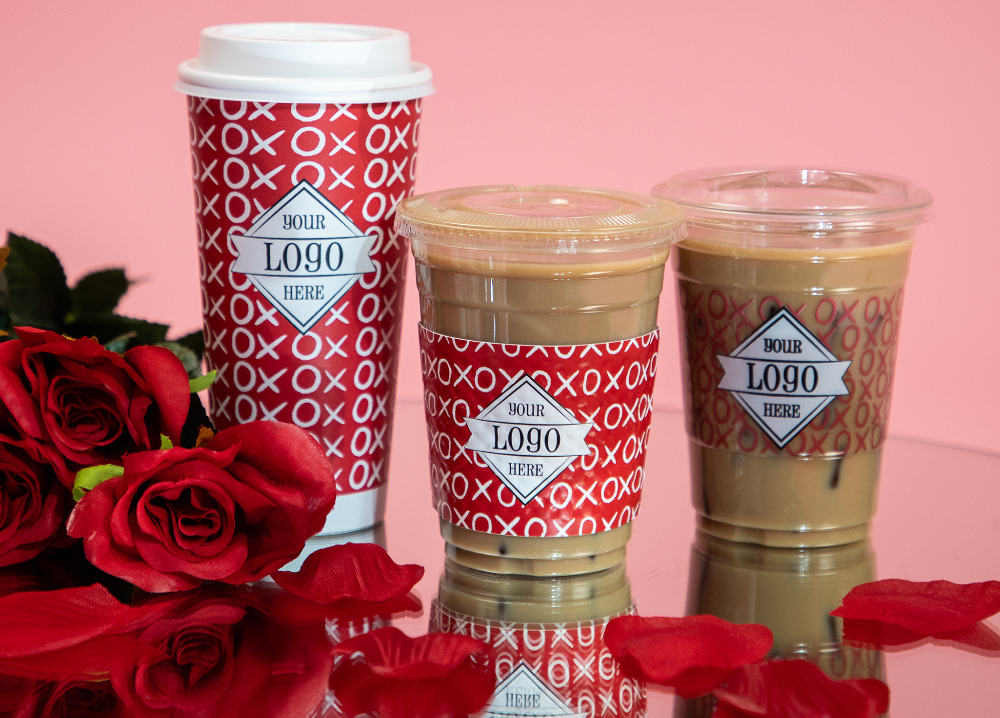 Valentine's Day themed cups on a mirror with rose petals and pink backdrop.