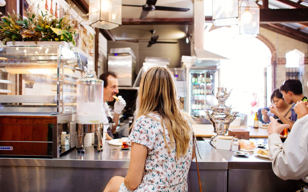 A woman sits at the bar of a restaurant.