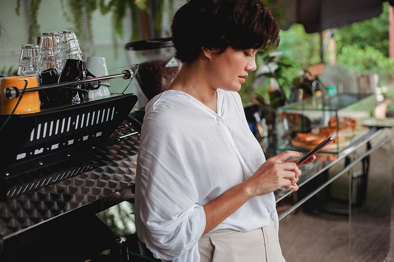 Woman scrolling through her phone in an outdoor cafe.