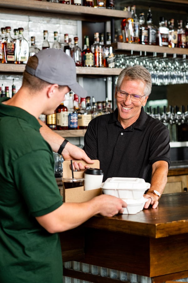 A customer picks up a to-go order from a bar.