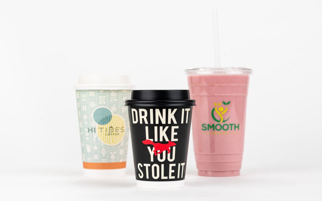 Two custom printed coffee cups and a custom printed plastic cup staged on a white table with white background.