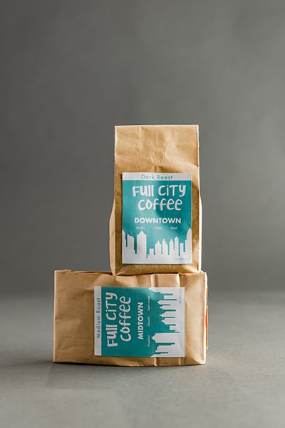Your Brand Cafe Two bags of coffee grounds boast custom stickers with the Full City Coffee logo