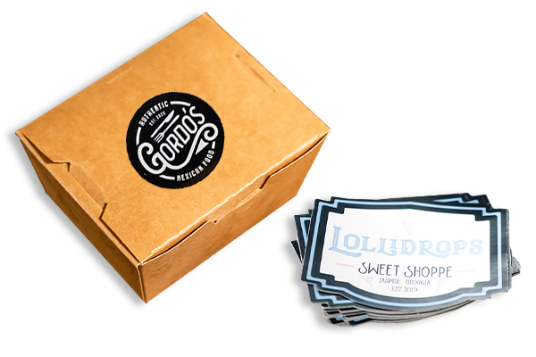 master-collection A paper to-go box with a label and a stack of custom printed vinyl stickers